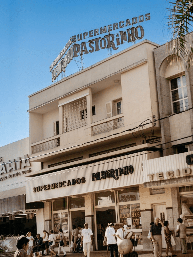 Fachada do Supermercados Pastorinho em Araçatuba-SP, com letreiro no topo do prédio e movimento de pessoas na calçada em frente ao supermercado.