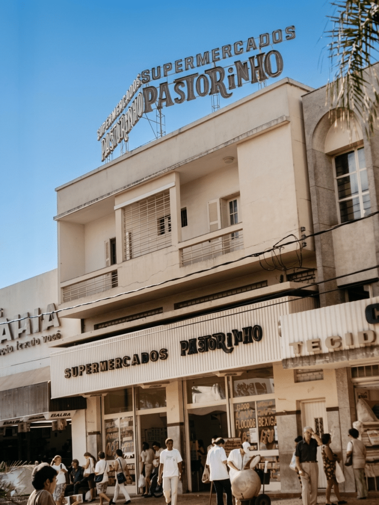 Fachada do Supermercados Pastorinho em Araçatuba-SP, com letreiro no topo do prédio e movimento de pessoas na calçada em frente ao supermercado.